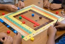 Mesa de Rummikub vista de cima, com peças coloridas formando sequências e grupos, destacando estratégia e competição entre jogadores
