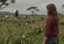Lana e sua companheira Mui atravessam uma paisagem alienígena pintada à mão, com vegetação exuberante e máquinas misteriosas ao longe.
